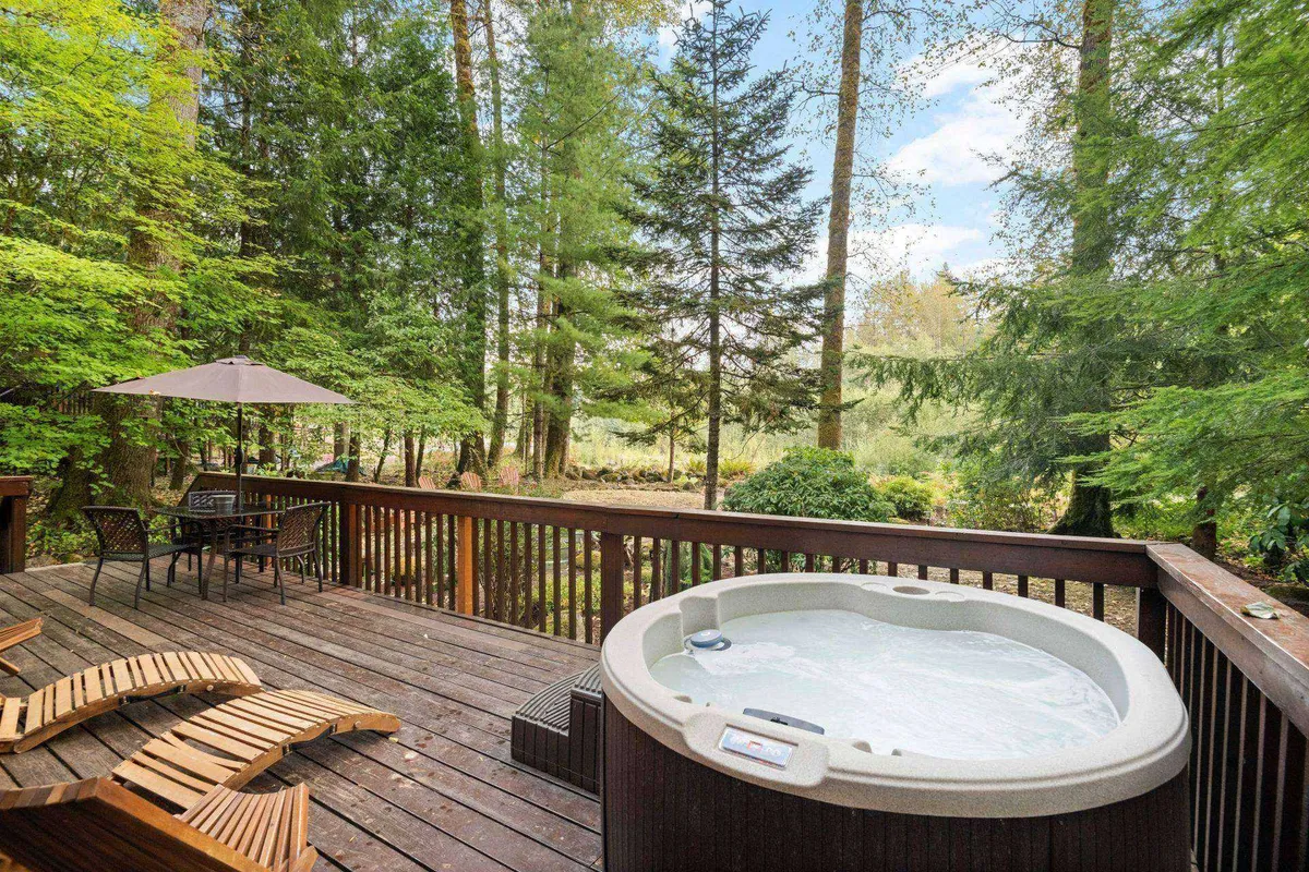 A spacious deck with a hot tub and outdoor seating area set amidst tall trees. The relaxing atmosphere invites lounging and nature appreciation—activities that can be enjoyed with dogs by your side.